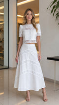 Front view of woman wearing white lace crop top and matching midi skirt set