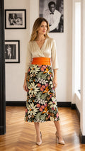 Full front view of model wearing cream and black floral midi dress with orange sash