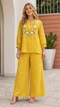 Front view of woman wearing yellow embroidered top and wide leg pants set