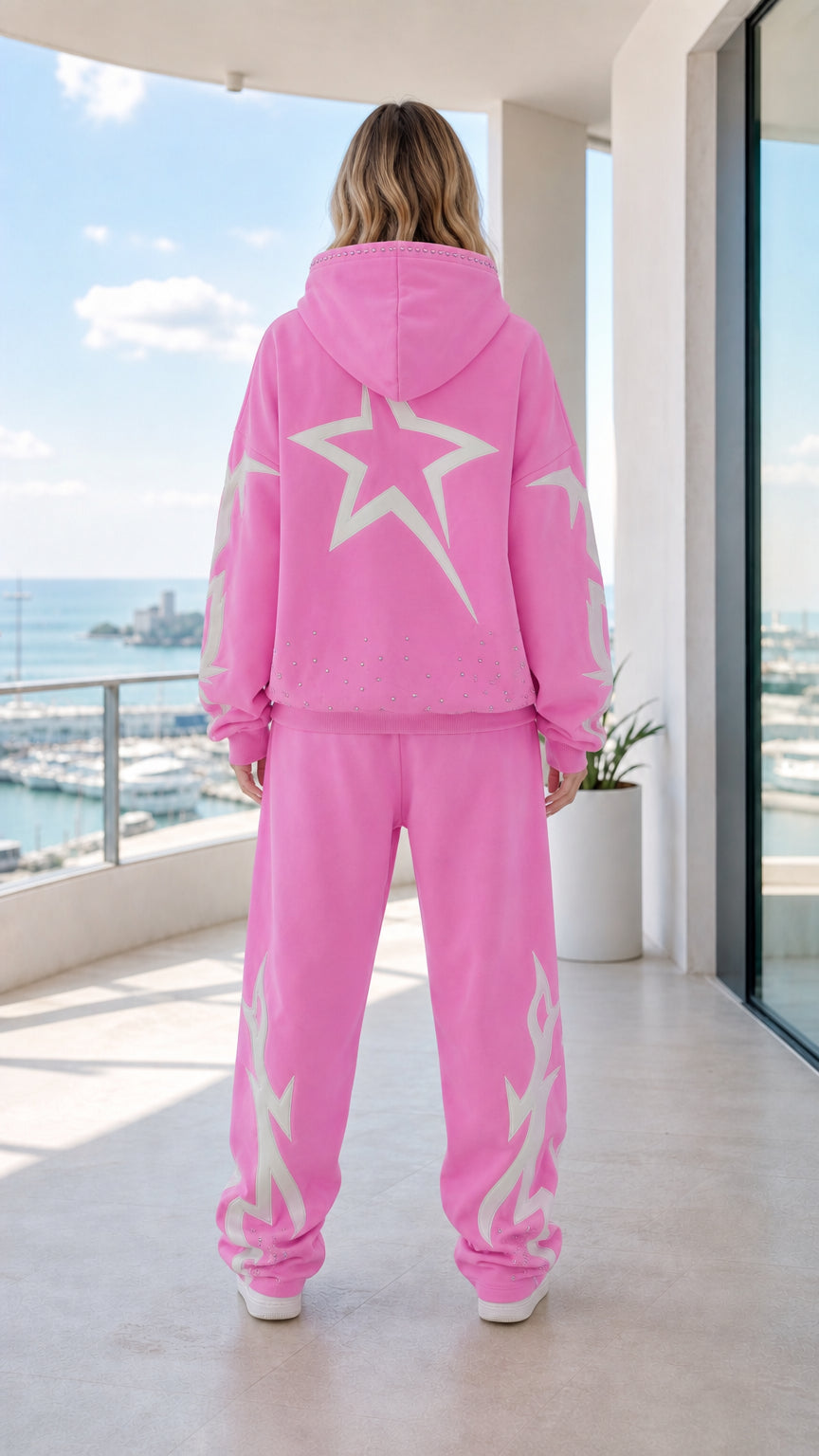 Back view of model showing large white star graphic on pink hoodie and sweatpants