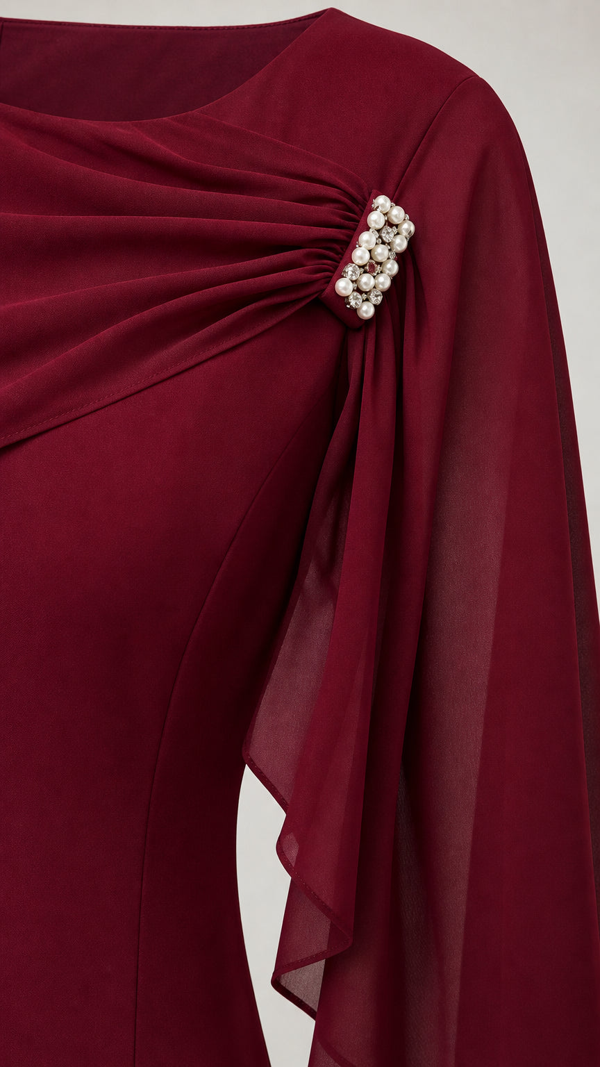 Close-up of pleated bodice and pearl brooch detail on burgundy dress
