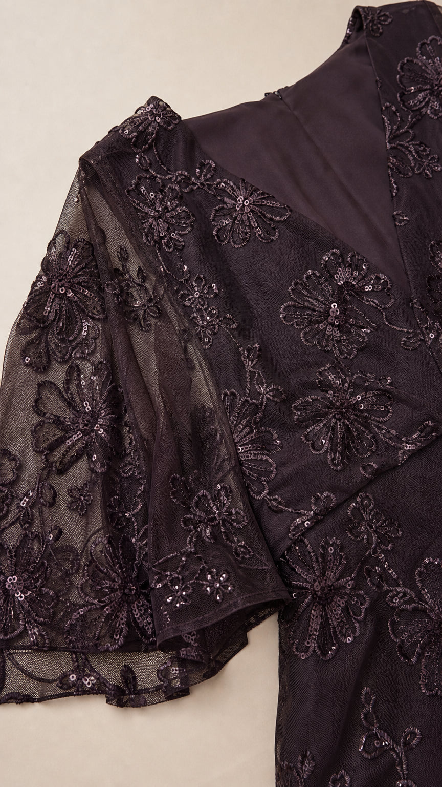 Close-up detail of floral sequin embroidery and sheer flutter sleeve on dark plum gown