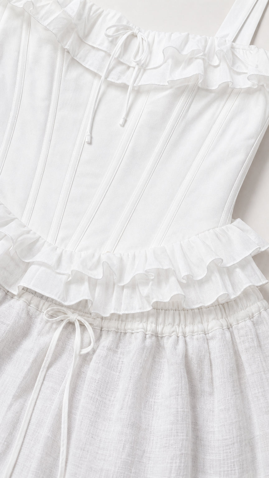 Close-up detail of white ruffled corset top and drawstring waistband